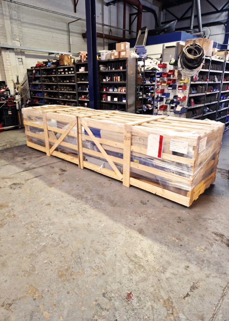 A new 2-post lift packed in a crate ready to be installed